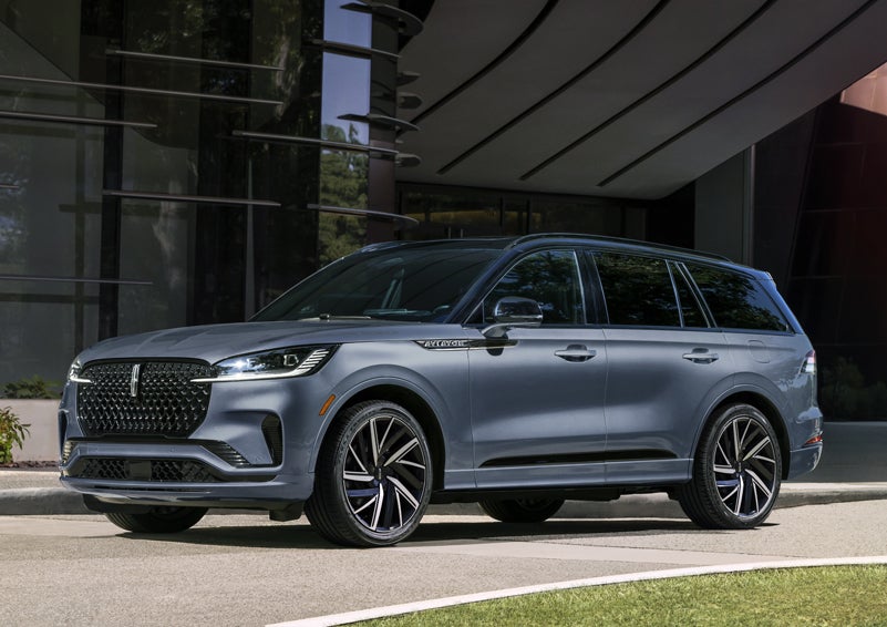 A gray 2025 Lincoln Aviator® SUV is parked outside a modern building showcasing the driver’s side of the vehicle. | Boulevard Lincoln in Millsboro DE