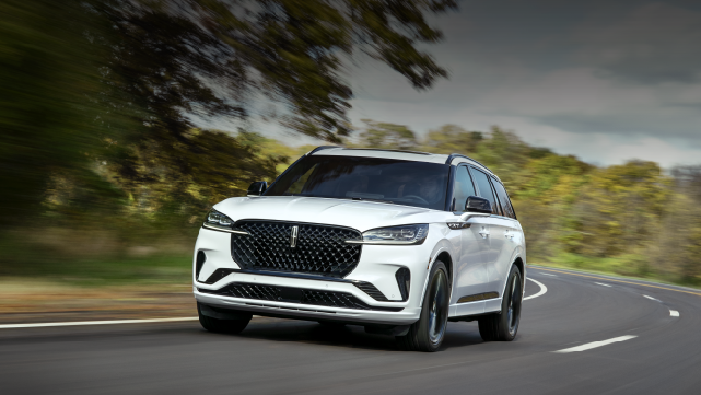 A white 2025 Lincoln Aviator® SUV is being driven down a road lined with trees. | Boulevard Lincoln in Millsboro DE