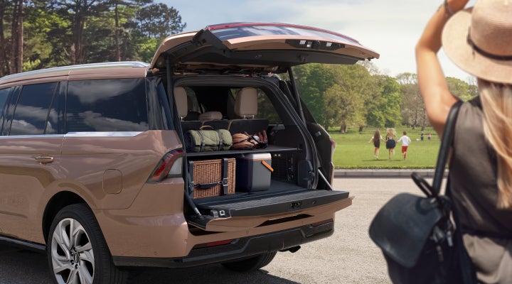 A woman approaches a parked 2025 Lincoln Navigator® SUV with its Split Gate open.