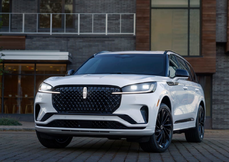 A 2026 Lincoln Aviator® Reserve model is shown with the available Jet Appearance Package parked near a restaurant. | Boulevard Lincoln in Millsboro DE