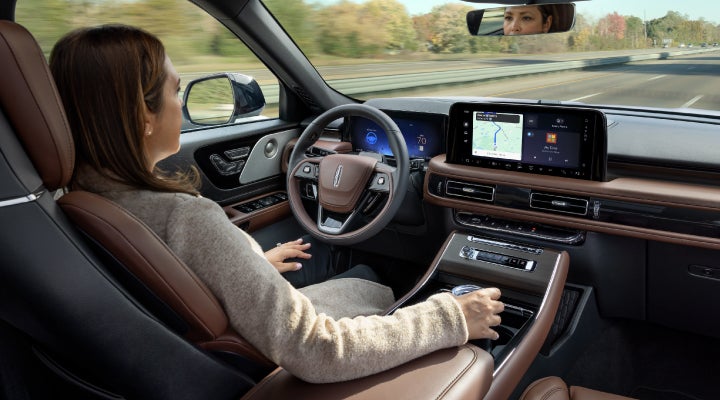 A 2026 Lincoln Aviator® SUV is being driven hands-free on a highway near a forest | Boulevard Lincoln in Millsboro DE