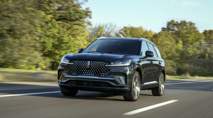 A 2026 Lincoln Black Label™ Aviator® SUV is being driven down a road lined with trees. | Boulevard Lincoln in Millsboro DE