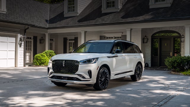 A white 2026 Lincoln Aviator® SUV is parked in the driveway of a luxury home. | Boulevard Lincoln in Millsboro DE