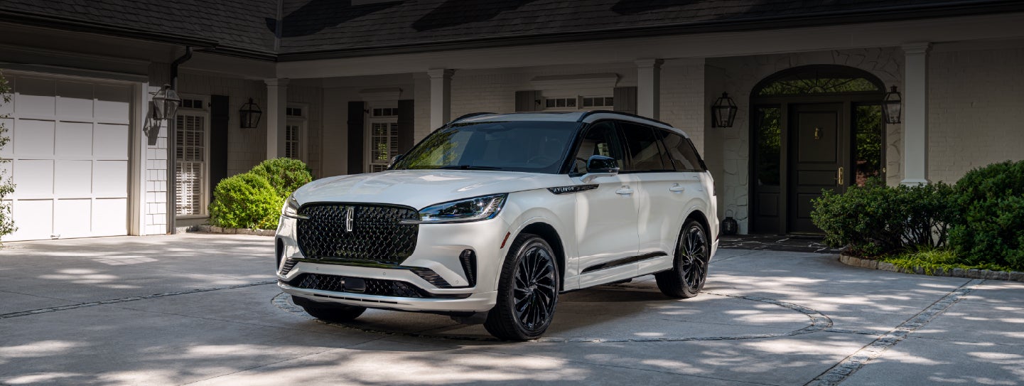 A white 2026 Lincoln Aviator® SUV is parked in the driveway of a luxury home. | Boulevard Lincoln in Millsboro DE