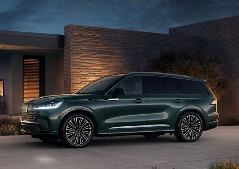 A green 2027 Lincoln Aviator® SUV is parked outside a contemporary home. | Boulevard Lincoln in Millsboro DE