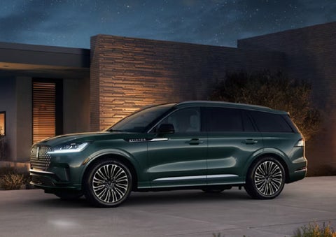 A green 2027 Lincoln Aviator® SUV is parked outside a contemporary home. | Boulevard Lincoln in Millsboro DE