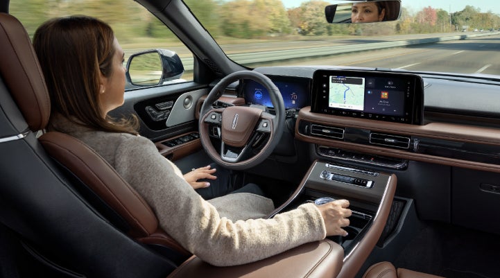 A 2027 Lincoln Aviator® SUV is being driven hands-free on a highway lined with trees. | Boulevard Lincoln in Millsboro DE